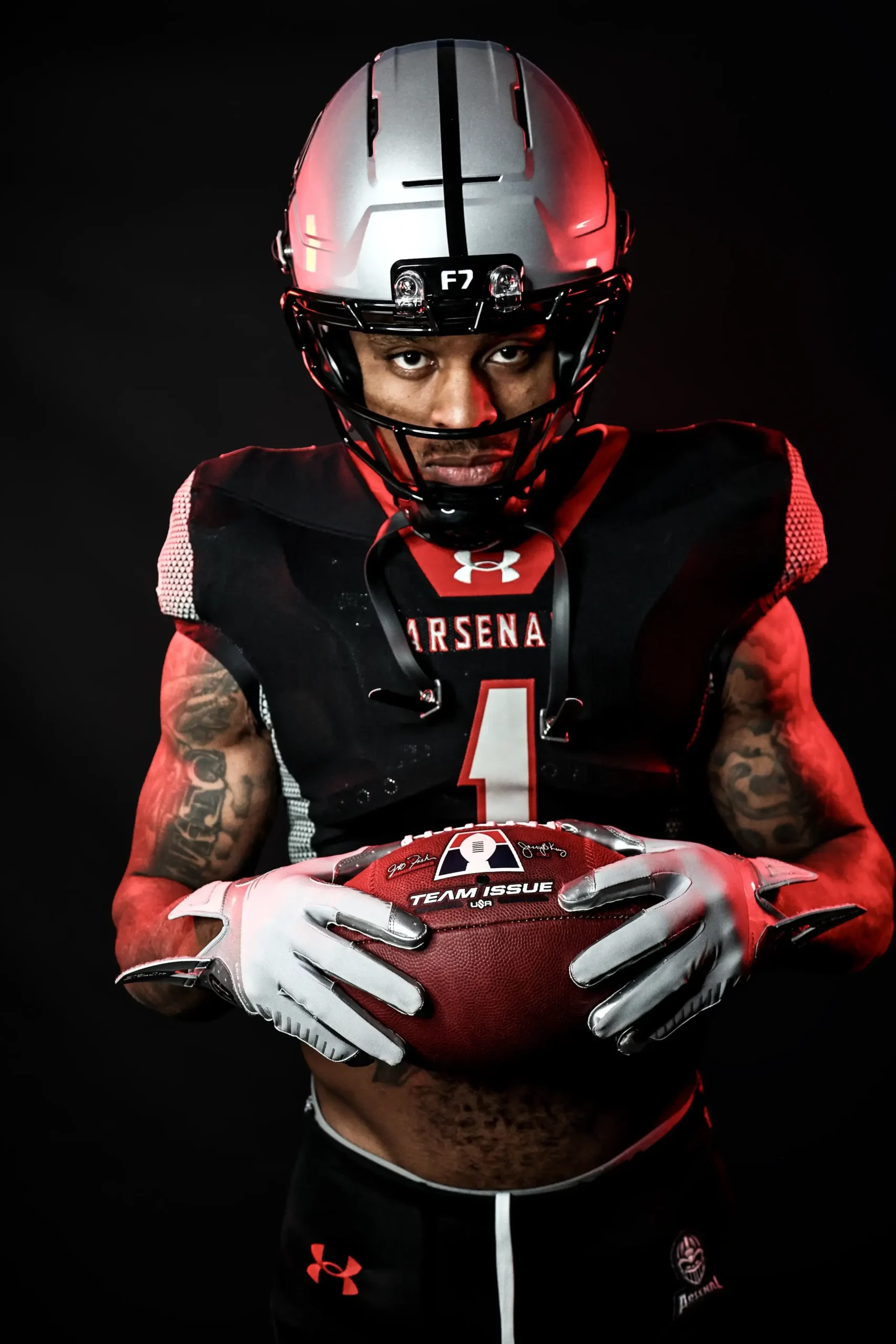 Michigan Arsenal player in full uniform holding an AF1 football