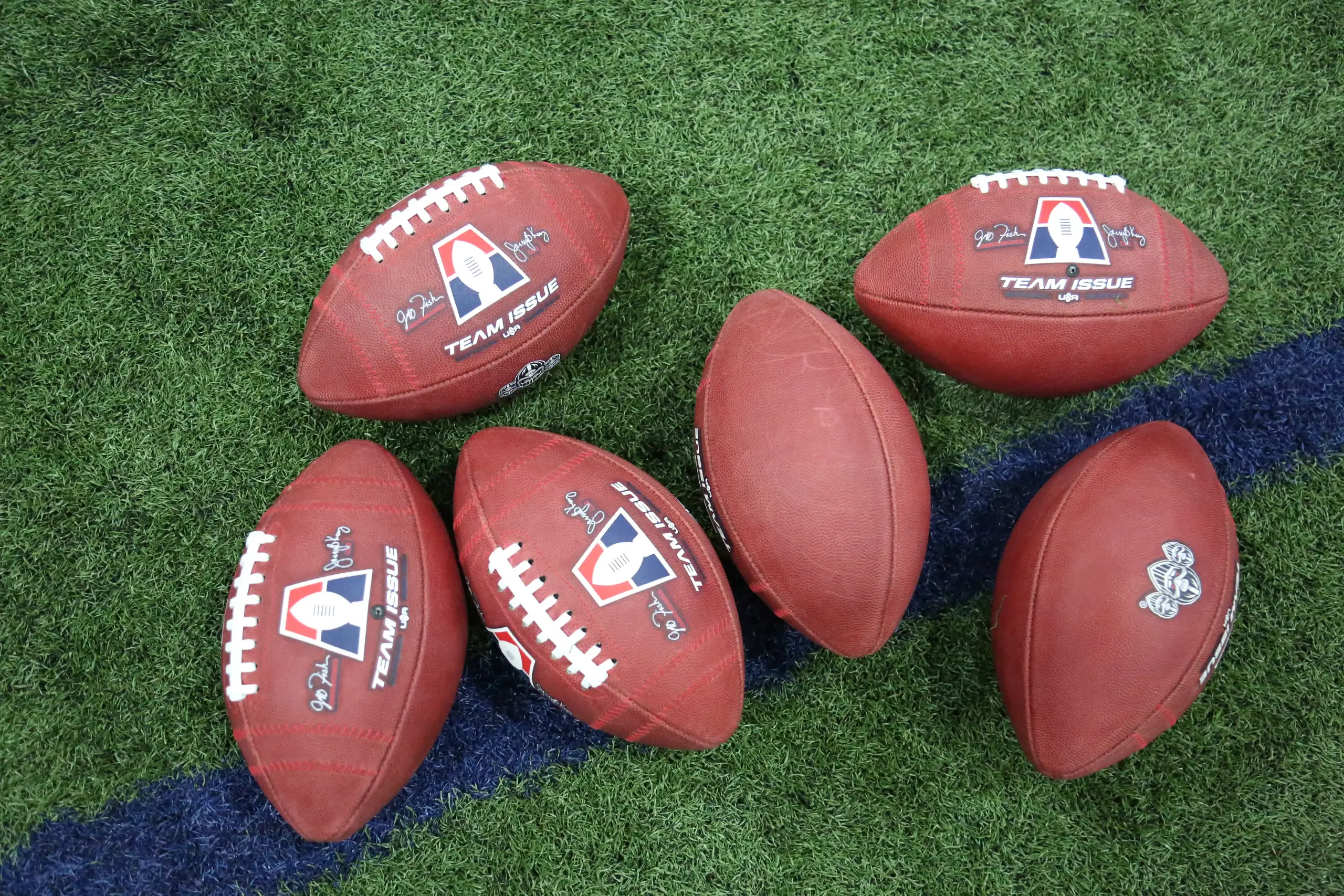 Pile of Michigan Arsenal and AF1 branded footballs on indoor turf